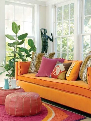 Sofá laranja com almofadas de onça.