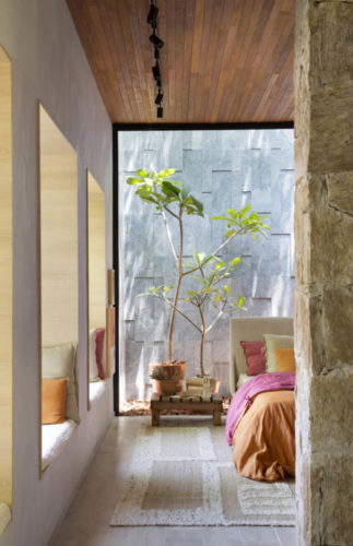 CASACOR RIO 2021 - Loft Contemporâneo. Teto revestido em madeira, parede e pedra separando o quarto do restante do loft