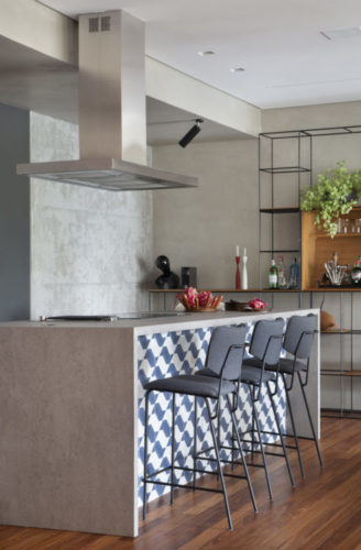 Cozinha integrada com a sala, a ilha revestida de porcelanato cinza e na frente azulejos azul e branco