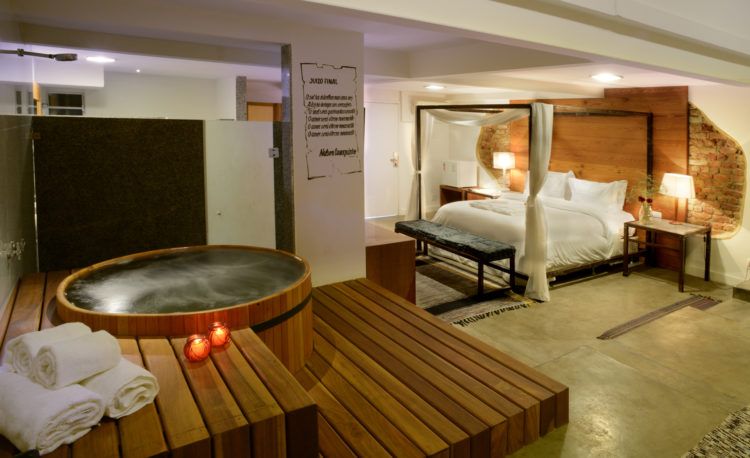 Quarto do hotel Le Chateau Lapa, cama dossel e um ofuro no deque de madeira 