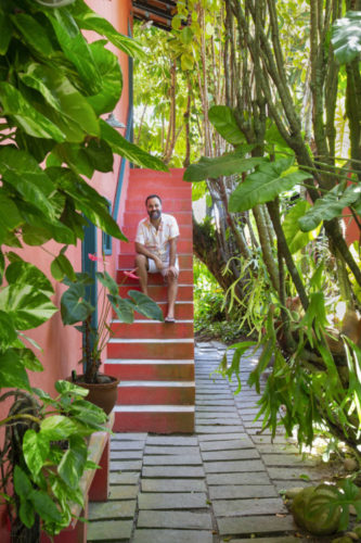 O arquiteto Francisco Palmeiro sentado na escada, da casa na região dos lagos. com jardim em torno