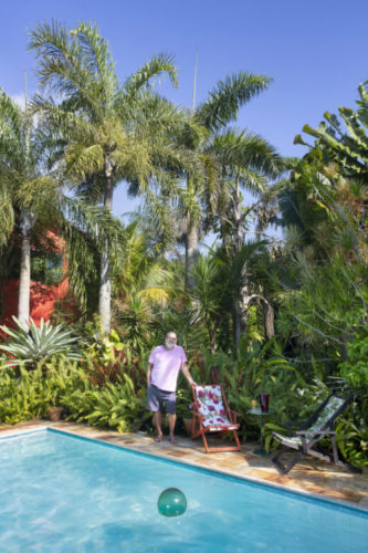 Foto do paisagista João Saldanha na beira da piscina na sua casa na região dos lagos, cercado por jardins exuberantes