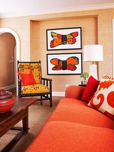 Sala com sofá laranja e quadros com borboletas.