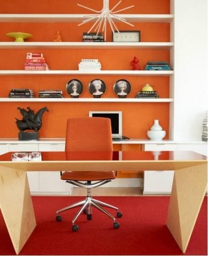 Estante no escritório com o fundo pintado de laranja.