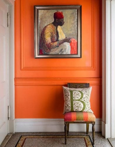 Hall de entrada decorado com lambri na parede toda pintada de laranja.