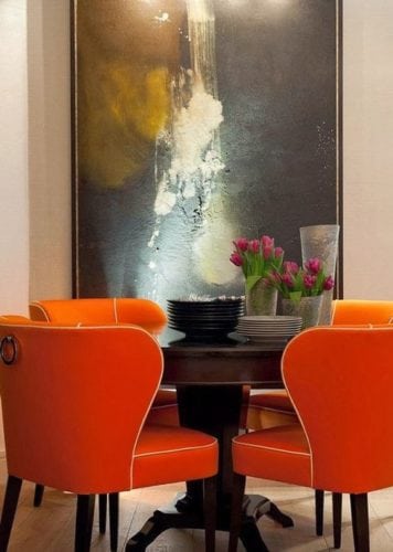 Sala de jantar com mesa redonda e cadeiras laranja.
