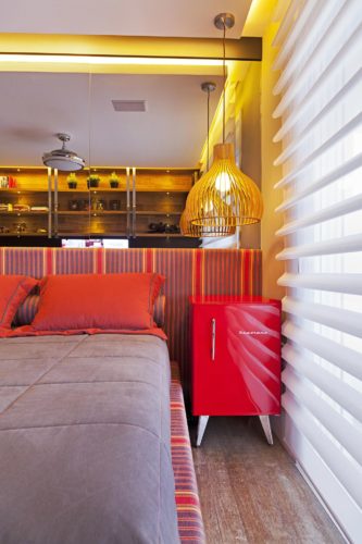 Frigobar na decoração, usado como mesa lateral da cama na cor vermelha destaque do quarto.