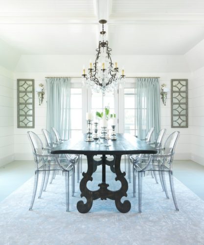 Sala de jantar com mesa preta e cadeiras em acrílico transparentes de Philippe Starck.