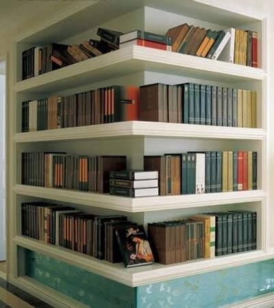 Biblioteca em casa, decorando com livros. Estante em quina da parede abriga a biblioteca da casa.
