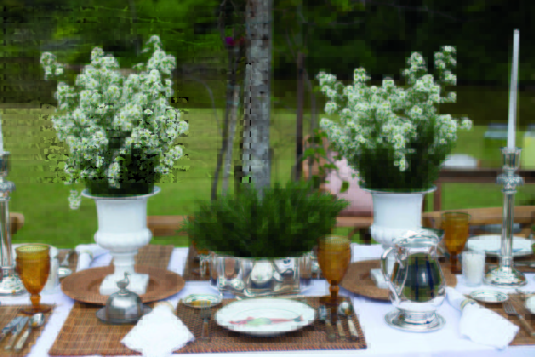 Inspirações para se criar mesas caprichadas. Mesa com arranjos de flor branca e decorada com peças em prata e rattan.