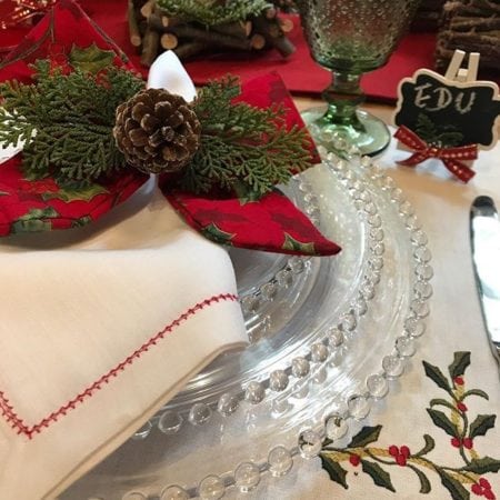 Mesa de Natal com porta-guardanapo de laço e com pinha enfeitando.