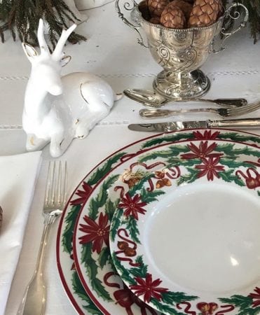 Mesa chic e tradicional de Natal. Toalha branca, faqueiro de prata e louça com tema natalino.