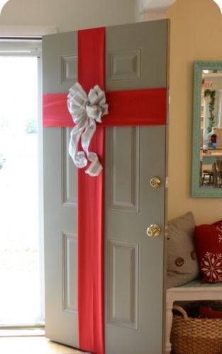 Porta de entrada decorada para o natal com laço vermelho.