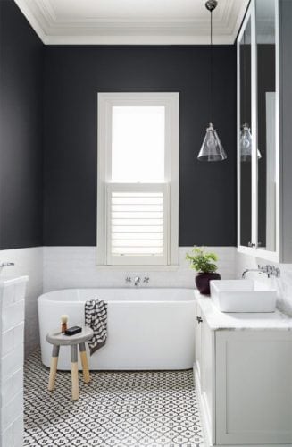 Banheiro preto e branco, meia parede pintado de preto fosco e piso em ladrilho hidráulico.