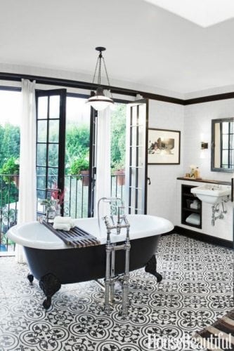 Destaque para a banheira preta e branca, no banheiro repleto de detalhes nessas cores.