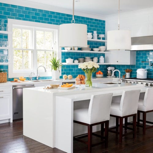 Ilha de cozinha com bancada de apoio , cuba e desnível para acomodar os assentos. Cozinha azul e branca.
