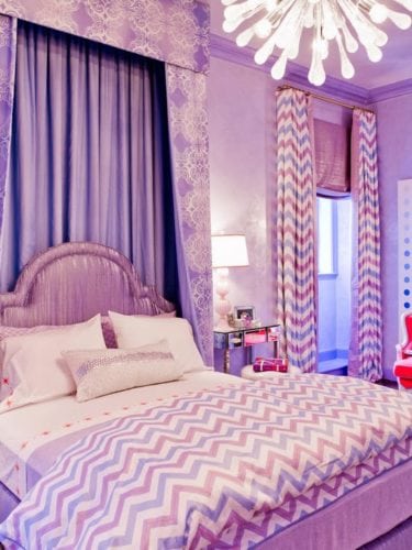 Quarto decorado com a cor lilás nas cortinas, na colcha e parede.