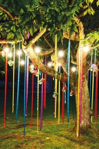 Ideias de decoração de Carnaval para festejar em casa.Arvore enfeitada com fitas coloridas e velas penduradas.