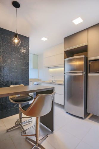 Com soluções de arquitetura, apartamento de 90m² ganha mais espaço e conforto. Bancada elevada na cozinha,com cadeiras altas em dourado.