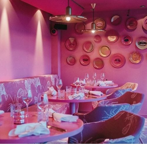 Restaurante MaMa kelly em Amsterdã decorado todo em Pink, inclusive parede e teto pintado dessa cor. Pratos rosa na parede decorando.