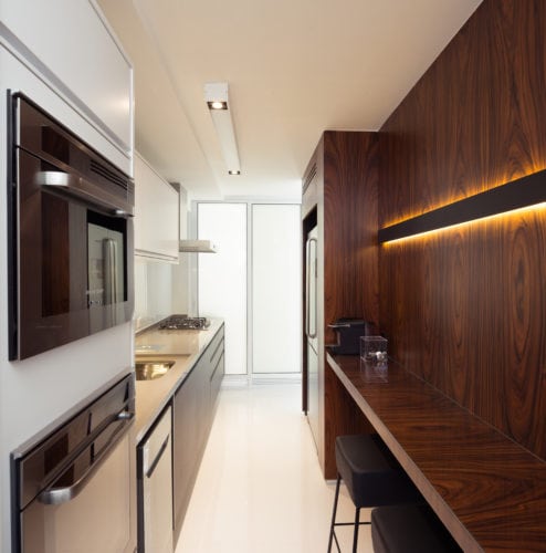 Apartamento pratico e sem excessos nos Jardins. Cozinha moderna com forno embutido e espaço para refeição forrada em madeira