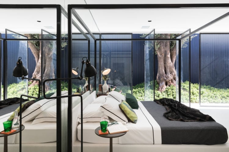 Espaço de João Armentano na Casa Cor SP 2018. Quarto com cama dossel em estrutura preta , com esquadrias abertas para o jardim.