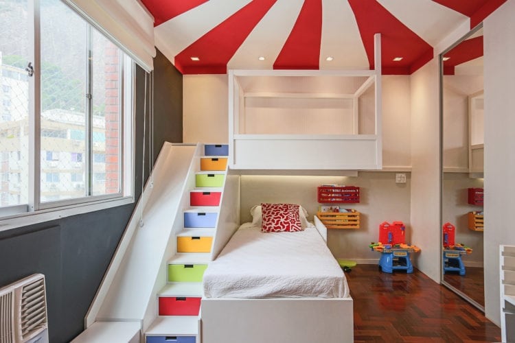 Decoração de quarto de criança, tem como inspiração, um Picadeiro. Faixas pintadas no teto, em vermelho e branco, rementem ao céu do picadeiro. E para aumentar o lado lúdico , um escorrega .