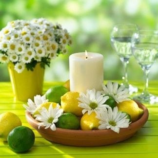 Dicas e inspirações para receber em casa nos jogos da Copa do Mundo 2022. Arranjo de mesa com limão verde e limão siciliano com uma vela no meio.