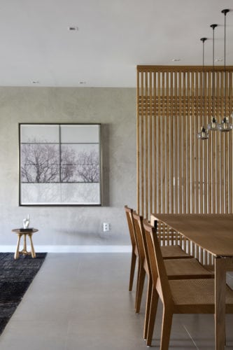 Sala de jantar com piso de porcelanato cinza e painel de madeira freijó vazado 
