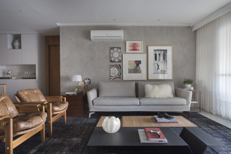 Sala com parede cinza em pintura especial, sofá em couro cinza e cadeiras do design Sergio Rodrigues