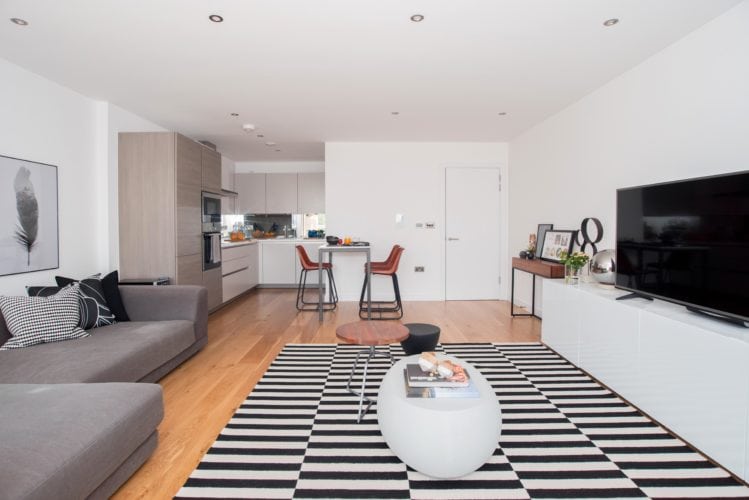 Arquitetas cariocas assinam o décor de apartamento em Londres. Sala ampla com tapete preto e branco. 