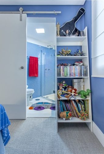 Quarto de menino decorado na cor azul e com banheiro em pastilhas azuis.