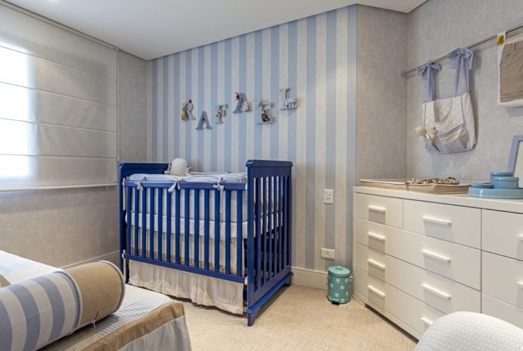 Quarto decorado de bebe, parede listrada de azul e branco.