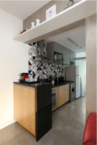 Décor masculino no pat de 63m. Cozinha aberta para a sala, com armários em madeira pinus e parede revestida com azulejos branco e preto.
