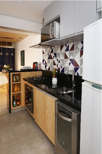 Décor masculino no pat de 63m. Cozinha aberta para a sala, com armários em madeira pinus e parede revestida com azulejos branco e preto.