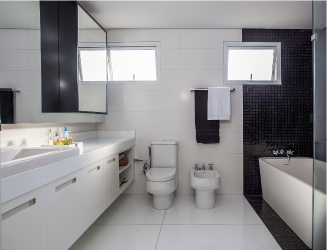 Urbanidade dá o tom para apartamento de família em SP. Banheiro em preto e branco com banheira branca.