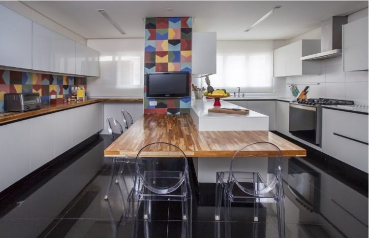 Urbanidade dá o tom para apartamento de família em SP. Cozinha com piso preto, armários brancos e com destaque do revestimento colorido em azulejo hidráulico.