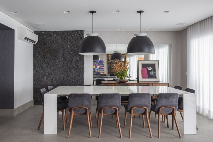 Urbanidade dá o tom para apartamento de família em SP. Sala de jantar com mesa branca, cadeiras cinzas e duas luminárias pendentes pretas.