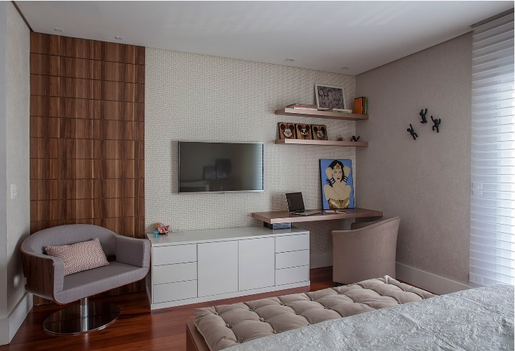 Urbanidade dá o tom para apartamento de família em SP. Bancada e tv na parede em frente a cama.
