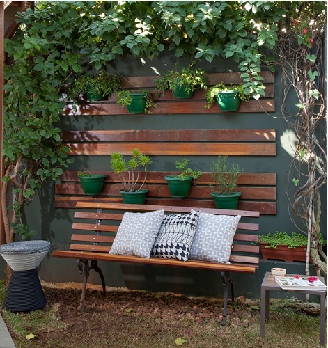 muro com horta vertical e um banquinho com almofadas.