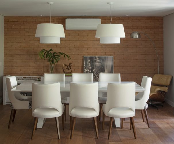 sala de jantar com moveis brancos e parede de tijolinhos no apartamento assinado por Bruno Moraes
