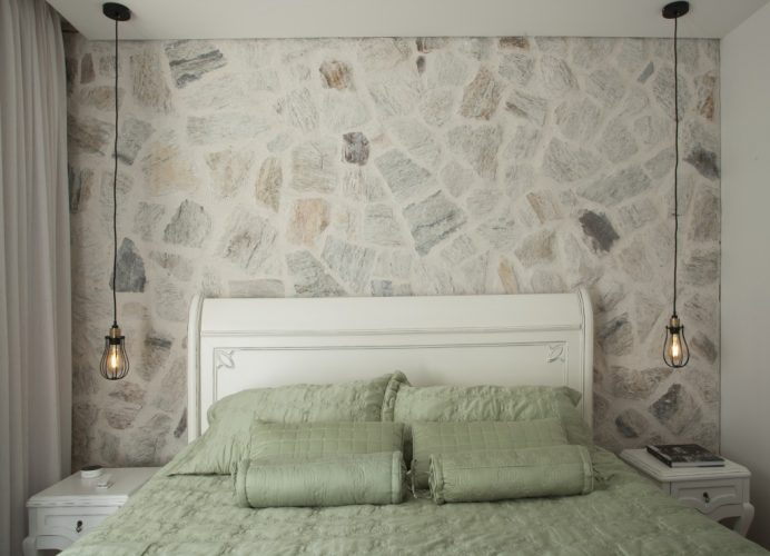 quarto do casal com paredes em pedras naturais no apartamento assinado por Bruno Moraes