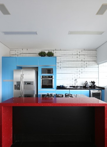 cozinha com armarios azuis e mesa vermelha no projeto da triarq arquitetura