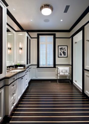 Rodapés pretos acrescenta personalidade ao Décor. Banheiro com piso preto listrado de branco, armarios e paredes brancas com detalhes em preto, como o rodapé e guarnição da janela e porta.