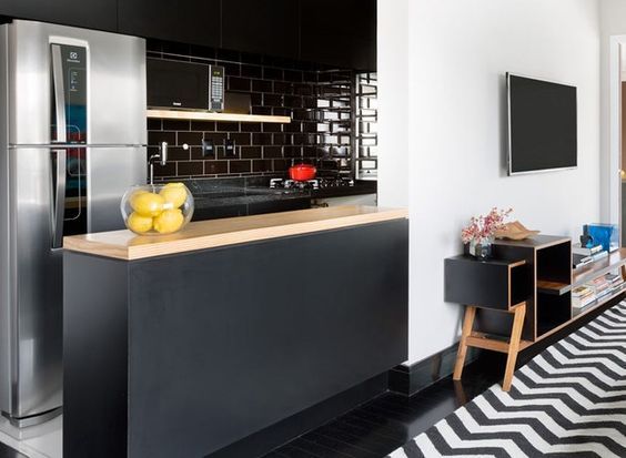 Rodapés pretos acrescenta personalidade ao Décor. Cozinha aberta para a sala que tem tapete na estampa chevron em preto e branco com o rodapé preto.
