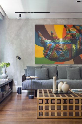 Sofa cinza embaixo do quadro de rinoceronte no apartamento assinado por Monique Pampolha e Hannah Cabral