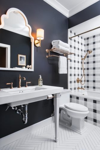Xadrex na decoração. Banheiro com a parede de funda da banheira revestida com revestimento xadrez em preto e branco