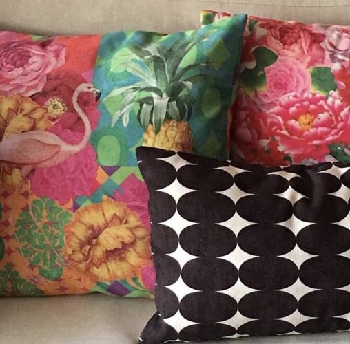 Mistura de estampas na decoração, almofadas rosa floridas e uma preta e branca.