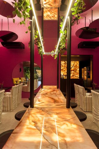 David Bastos assina restaurante Amado na CASACOR Bahia 2019, parede e teto pintado de rosa e espelhos redondos no teto.