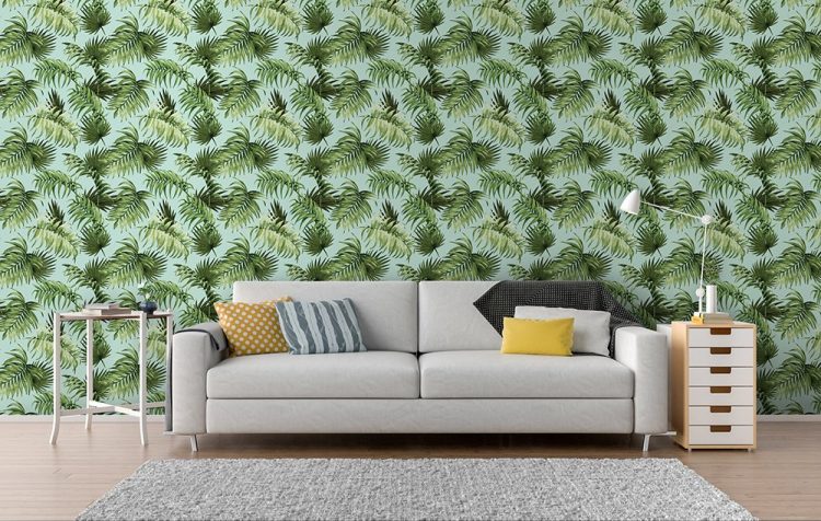 papel de parede com estampa de folhas e um sofá cinza